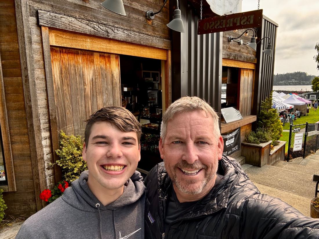 A father and son standing together outside the Aviator espresso stand on Bainbridge Island